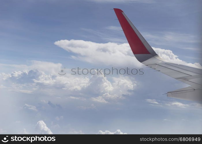 view of airplane wing and cloudscape in blue sky from aircraft window