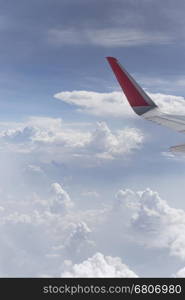 view of airplane wing and cloudscape in blue sky from aircraft window