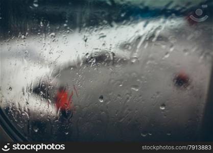 View of airplane wing at rainy day through window with water drops