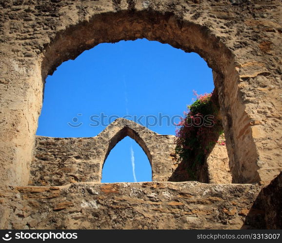 View of an old arch in San Juan Mission in Texas with modern jet trail in sky