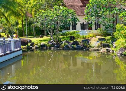 View of beautiful green pond and buildings of luxury hotel at tropical resort 