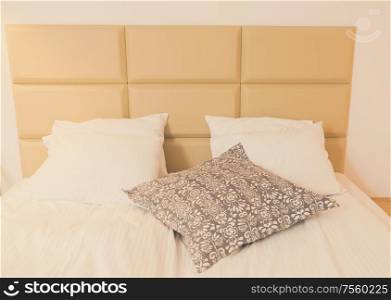 view of bed with white linen and gray pillows close up. bedroom interior closeup