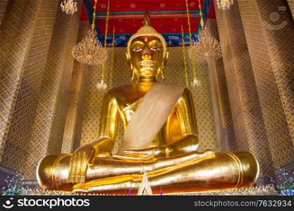 View of big golden statue of sitting Buddha in famous buddhist temple. Wat Kanlayanamit, Bangkok, Thailand