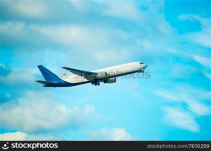 View of big white flying plane on blue sky and clouds background