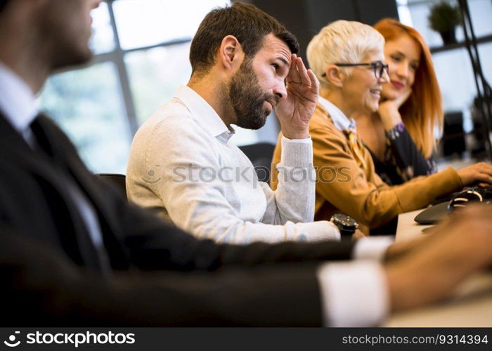 View of businessman executive in group meeting with other businessmen and businesswomen in modern office with computer