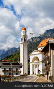 view of church, tower and street in italian town Auronzo di Cadore