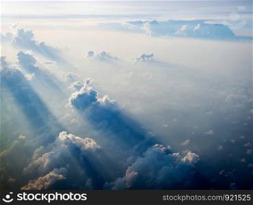 View of clouds from plane in beams of the sunset, sky as seen through window of an aircraft