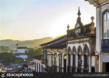 View of colonial style houses facade and historic baroque church in the background on the hills of Ouro Preto city, Minas Gerais state, Brazil. View of colonial style houses facade and historic baroque church in Ouro Preto