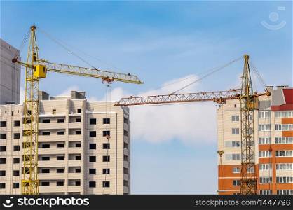 View of Construction Site with Two Apartment Buildings and Cranes. Blue Sky and Clouds Background