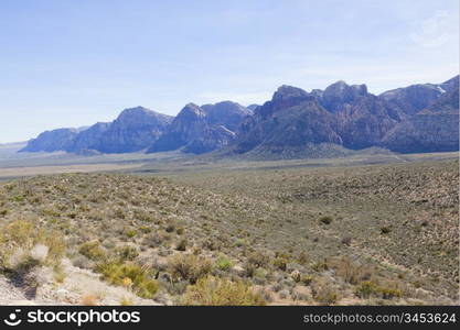 View of dry landscape and red rock formations of the Mojave Desert..