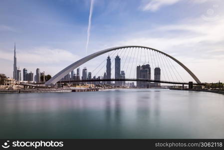 View of Dubai Skyline with the iconic Burj Khalifa and a pedestrian brige passing over the water canal. Dubai Skyline from Water Canal
