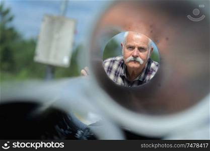 View of elderly man through metal tube