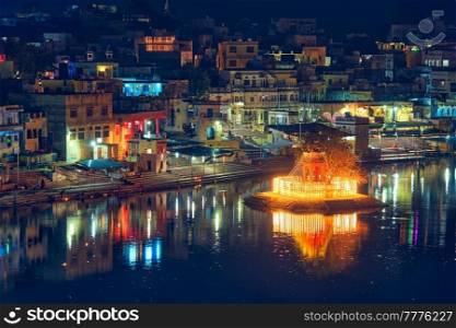 View of famous indian hinduism pilgrimage town sacred holy hindu religious city Pushkar with Brahma temple, aarti ceremony, lake and ghats illuminated at sunset. Rajasthan, India. Horizontal pan. View of indian pilgrimage sacred city Pushkar with Pushkar ghats. Rajasthan, India. Horizontal pan
