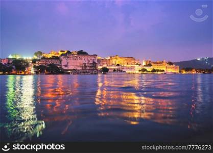 View of famous romantic luxury Rajasthan indian tourist landmark - Udaipur City Palace in the evening twilight with dramatic sky - panoramic view. Udaipur, India. Udaipur City Palace in the evening view. Udaipur, India
