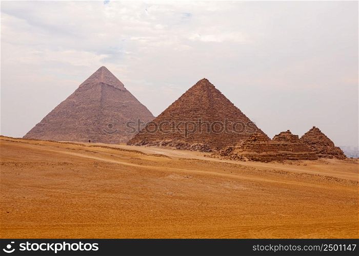 View of Giza Valley in Sahara Desert in Cairo, Egypt, with The Great Pyramid of Giza in overcast cloudy day.