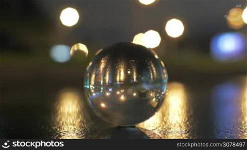 View of glass sphere imaging inverted cityscape with traffic road against blurred bokeh background in the evening