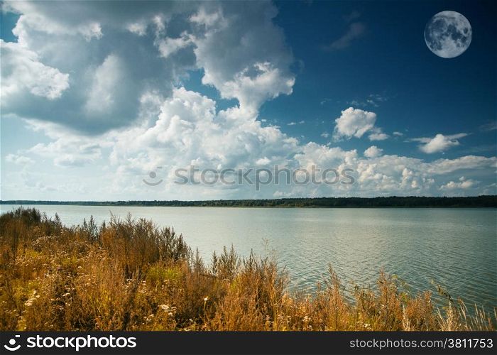 view of green fields, river and forest on background of storm clouds