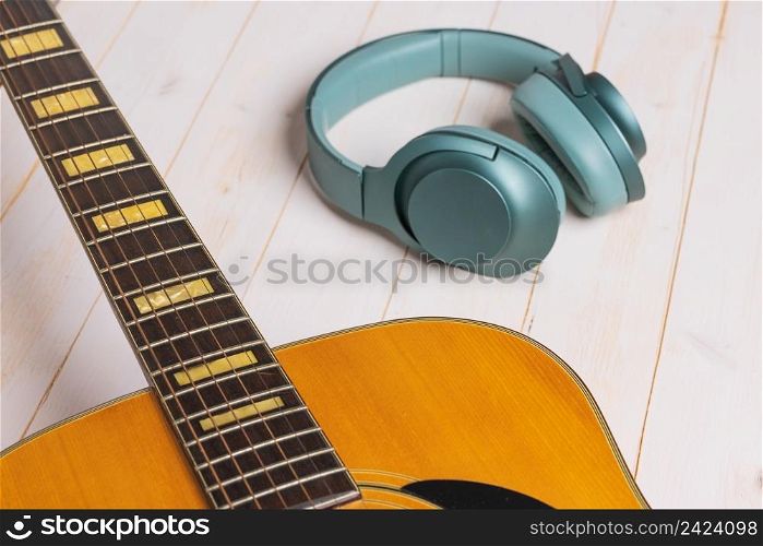 view of guitar and green headphones on wooden background, closeup