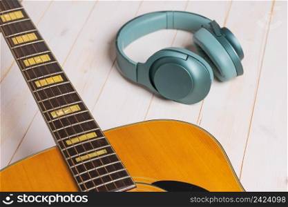 view of guitar and green headphones on wooden background, closeup