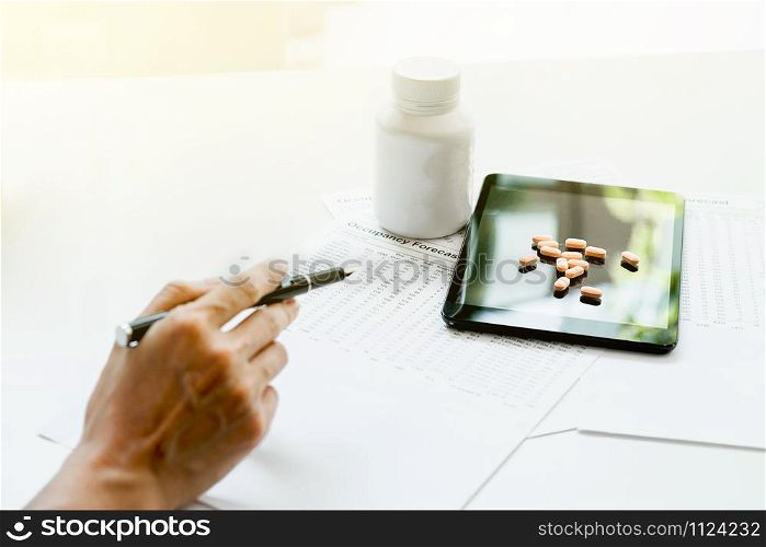 View of hand&rsquo;s doctor pointing to pad, drug and equipment on foreground table, Health care and Medical concept.