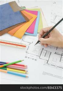 View of hand writing on architectural drawing with fabric sample, scale and color pencil
