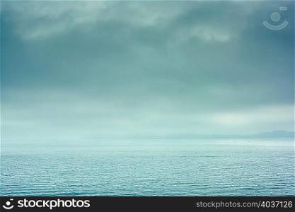 View of horizon over calm water with dramatic stormy sky