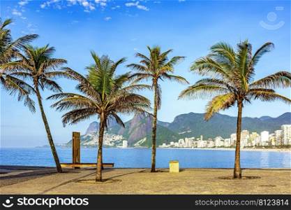 View of Ipanema beach in Rio de Janeiro on a summer morning with palm trees, rocks, hills, ocean and buildings. View of Ipanema beach in Rio de Janeiro at morning