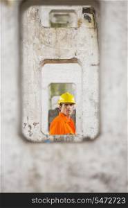 View of male architect through pillars at construction site