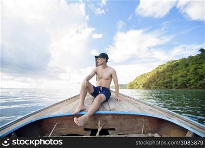 View of man in swimsuit enjoying on thai traditional longtail Boat over beautiful mountain and ocean, Phi phi Islands, Thailand