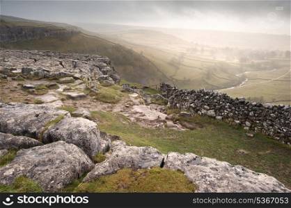 View of misty Malham Dales from limestone pavement above Malham Cove in Yorkshire Dales National Park