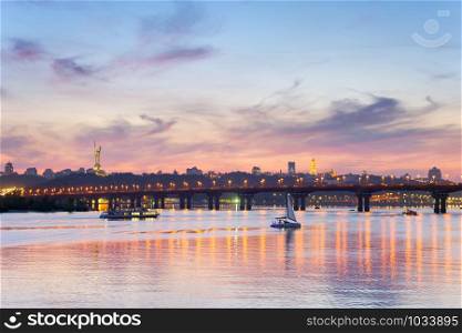 View of Mother Motherland monument above Dnipro river with Paton bridge and Kiev city at sunset, Ukraine