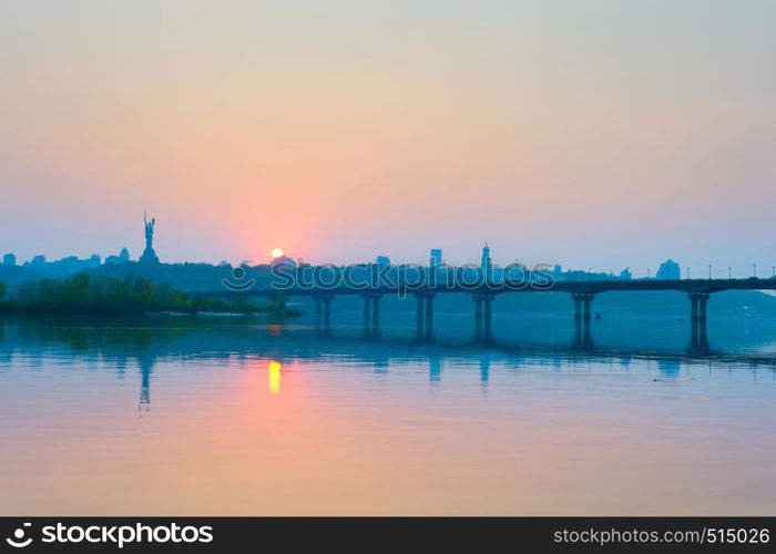 View of Mother Motherland monument above Dnipro river with Paton bridge and Kiev city at sunset, Ukraine