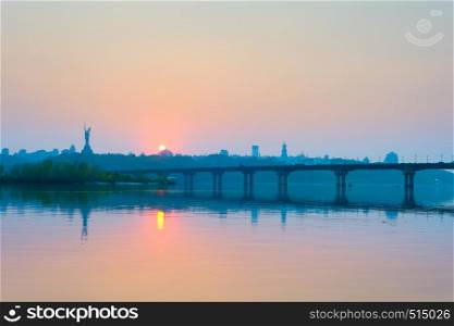 View of Mother Motherland monument above Dnipro river with Paton bridge and Kiev city at sunset, Ukraine