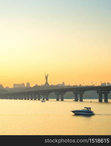 View of Mother Motherland monument, motor boat on Dnipro river, Paton bridge. Kiev, Ukraine