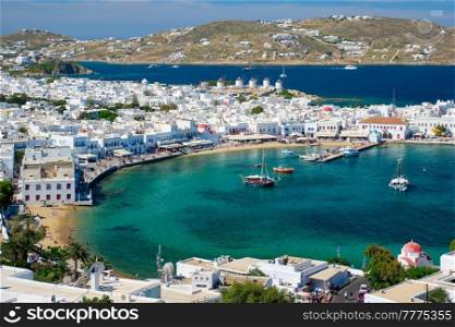 View of Mykonos town Greek tourist holiday vacation destination with famous windmills, and port with boats and yachts. Mykonos, Cyclades islands, Greece. Mykonos island port with boats, Cyclades islands, Greece