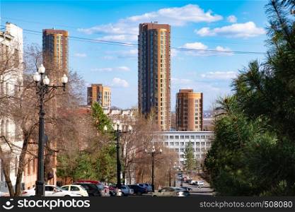 View of one of the streets of Khabarovsk in the daytime against a blue bright sky and white clouds. The combination of ancient architecture with modern buildings.. Khabarovsk, Russia - Sep, 26, 2018: The view of the Shevchenko street and Lenina street. Old houses combined with modern high-rise towers.