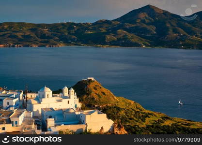 View of Plaka village on Milos island with traditional greek white houses with Greek Orthodox christian churck on sunset. Plaka town, Milos island, Greece. View of Plaka village on Milos island on sunset in Greece