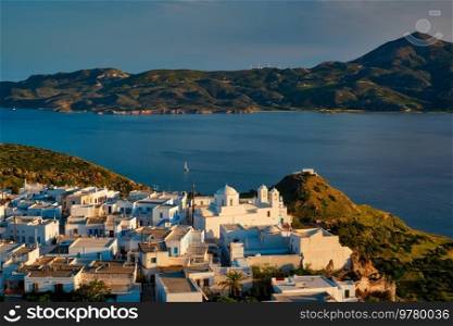 View of Plaka village on Milos island with traditional greek white houses with Greek Orthodox christian churck on sunset. Plaka town, Milos island, Greece. View of Plaka village on Milos island on sunset in Greece