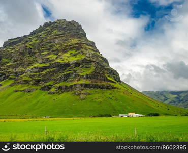 View of rocky mountain and a farm house in the rural of Iceland in summer