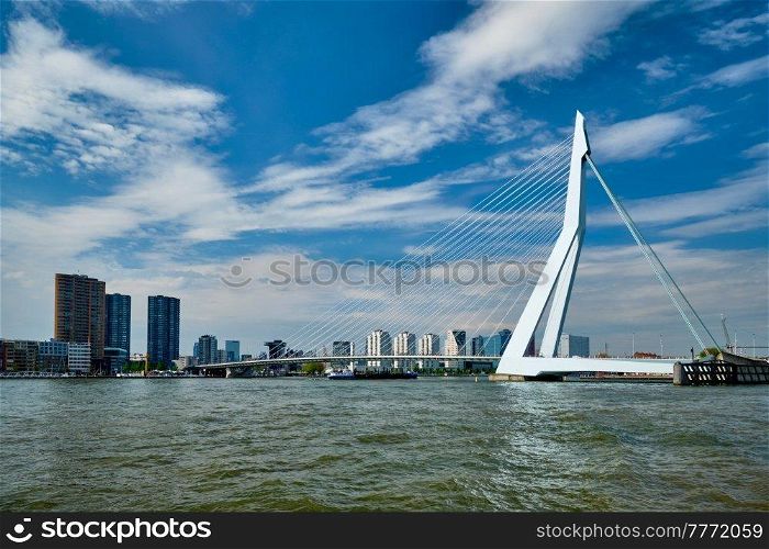 View of Rotterdam skyline over Nieuwe Maas with Erasmusbrug bridge and skyscrapers with cargo ships barge coming under the bridge. Rottherdam, the Netherlands. View of Rotterdam over Nieuwe Maas with Erasmusbrug bridge. Rottherdam, the Netherlands