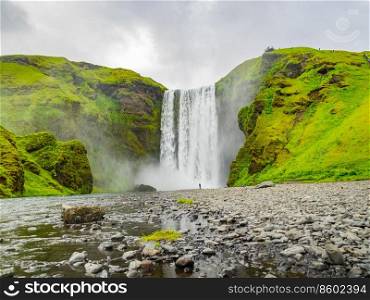 View of Skogafoss waterfalls in a cloudy day in summer Iceland