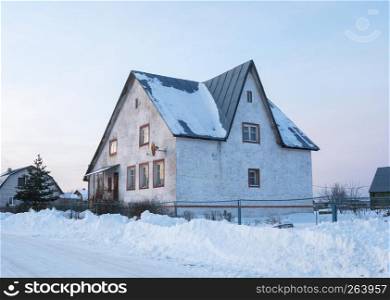 View of suburban concrete mansion in winter time at sunset