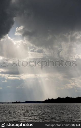 View of sunbeam through clouds over a lake, Lake of the Woods, Ontario, Canada