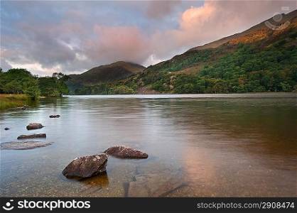 View of sunrise over Llyn Gwynant towards landscape of Yr Afan mountain in Snowdonia National Park