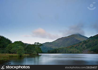 View of sunrise over Llyn Gwynant towards landscape of Yr Afan mountain in Snowdonia National Park