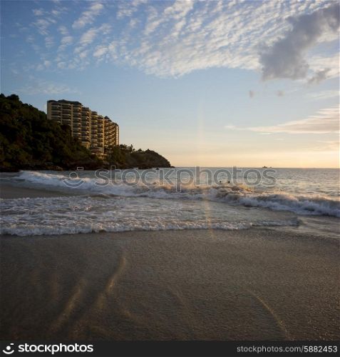 View of surf on the beach at sunsest with apartment buildings in background, Ixtapa, Zihuatanejo, Guerrero, Mexico