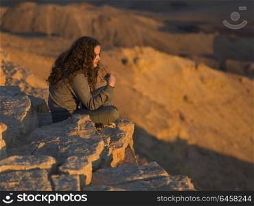 View of teenage girl sitting on rock in desert, Makhtesh Ramon, Negev Desert, Israel