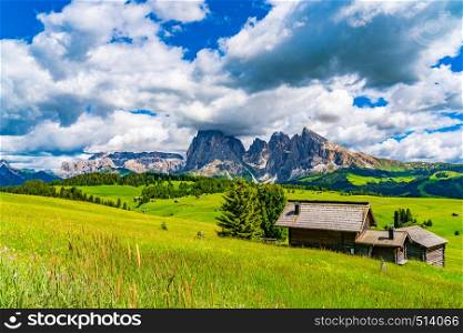 View of the Alpine Green Plateau Seiser Alm with the Dolomites Mountain Langkofel Group and the Italian Cottage in South Tyrol Italy