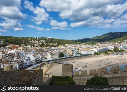 View of the beach, the promenade and the historic part of the city from the fortress of the old town (Tossa de Mar, Spain)