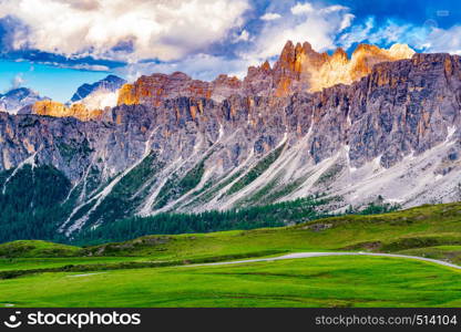 View of the beautiful Dolomites mountain at the Giau Pass Italy with the evening light on the peak and road pass through the grassy field